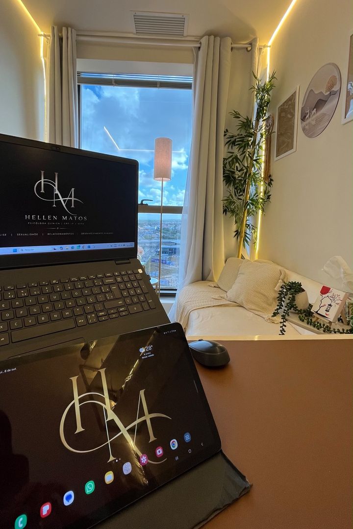 Notebook e tablet com o monograma HM em primeiro plano, com o bambu, os quadros e o sofá ao fundo.